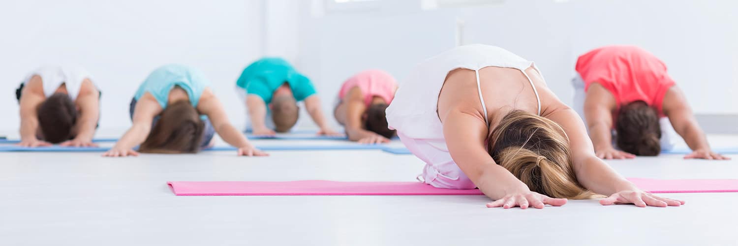 Yogagruppe mit Yogatrainer beim Üben